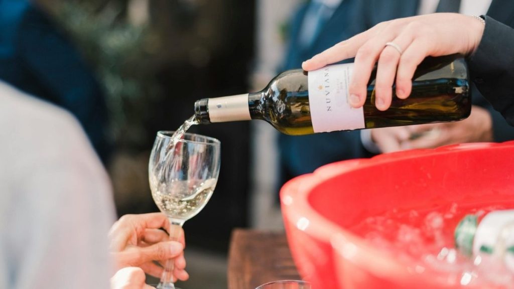 kelner die wijn in een glas schenkt