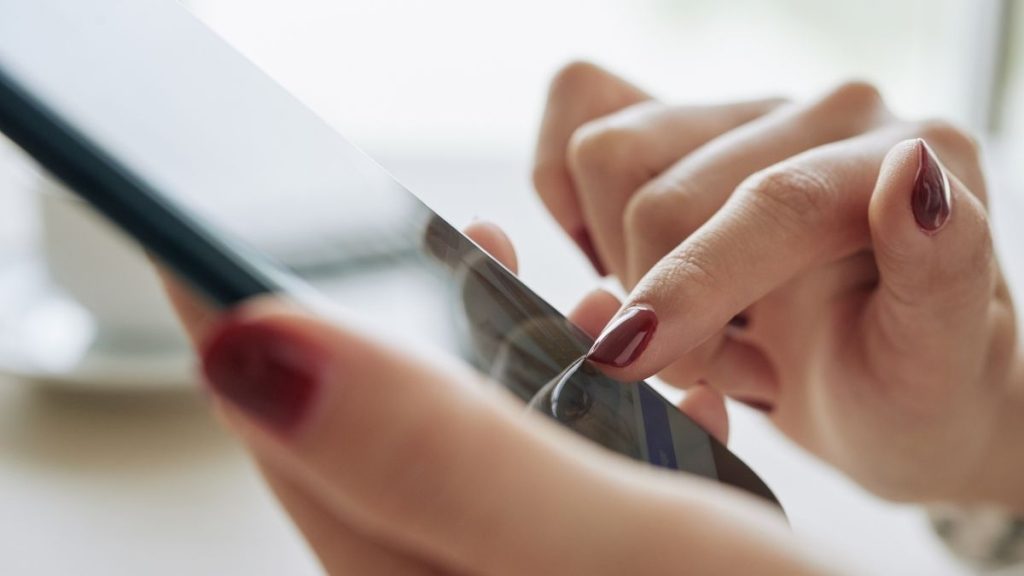 close-up van de vingers van een vrouw die sms't op een mobiel