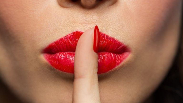vrouw die een vinger op haar lippen houdt om een geheim te bewaren