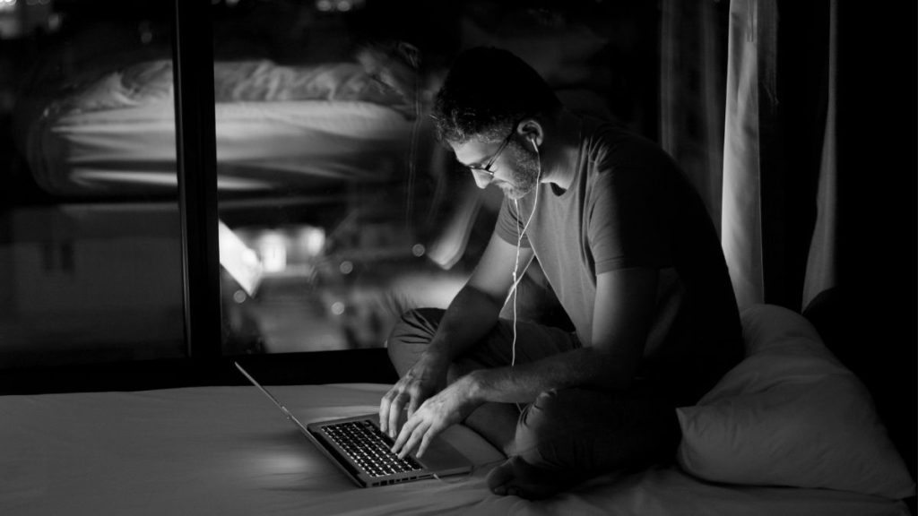 nachttafereel met een man die op een bed zit met een laptop