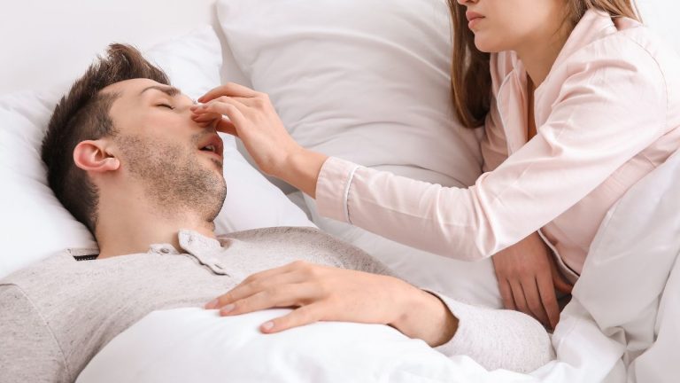 vrouw die de neus van een man dichtknijpt om zijn gesnurk te stoppen