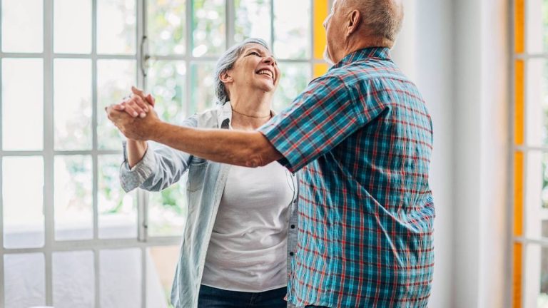 man en vrouw die vrolijk dansen in hun woonkamer