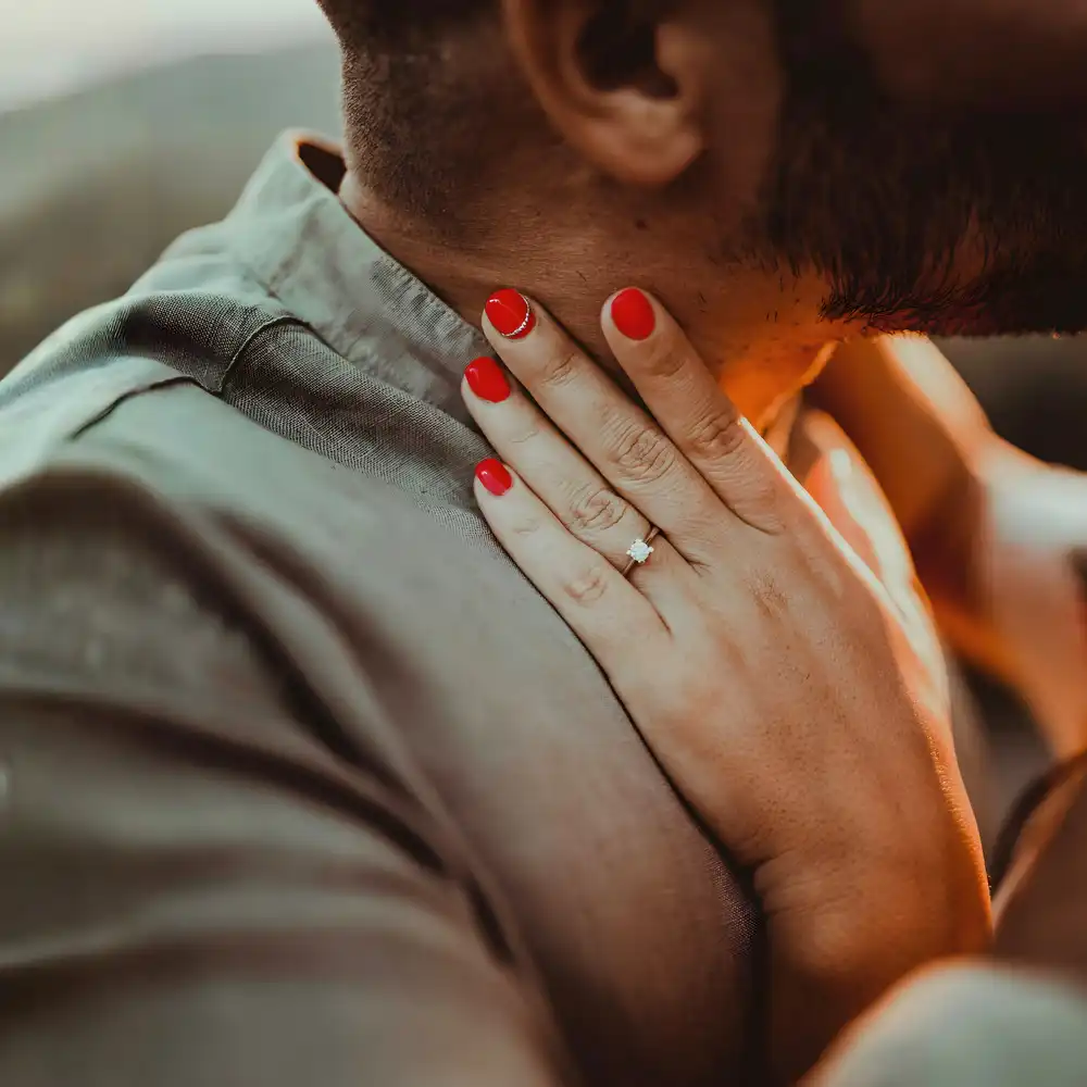 Een trouwring aan de vinger van een vrouw en een man in de achtergrond