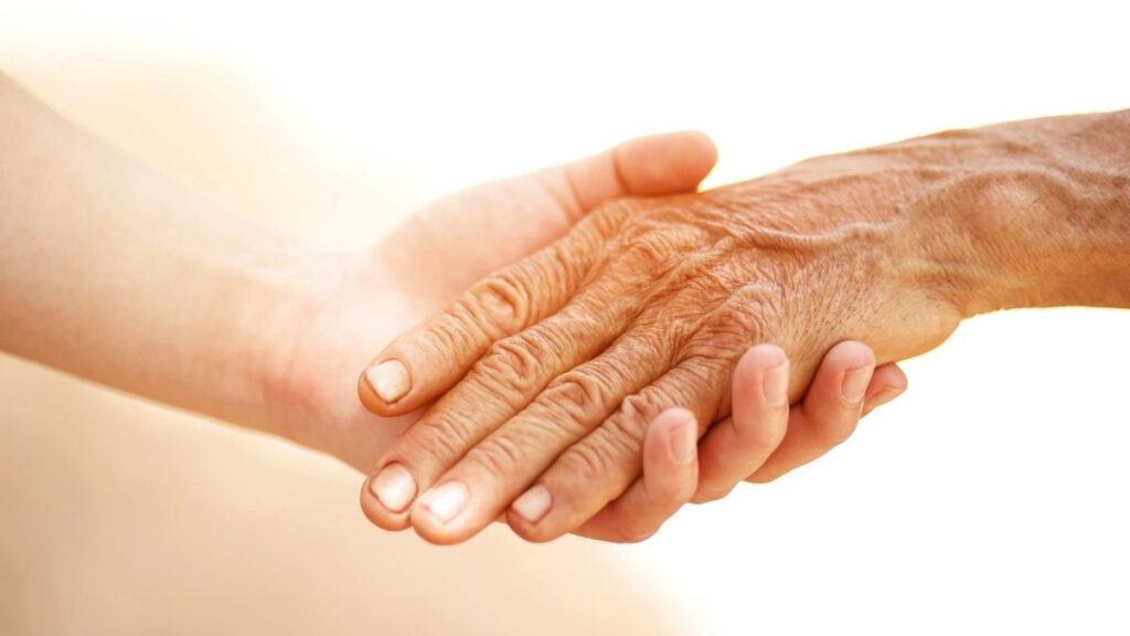 Een jongere die de hand van een oudere vasthoudt. Dit symboliseert generatieverschillen