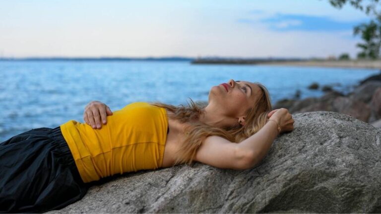 vrouw die dagdromend op een rots