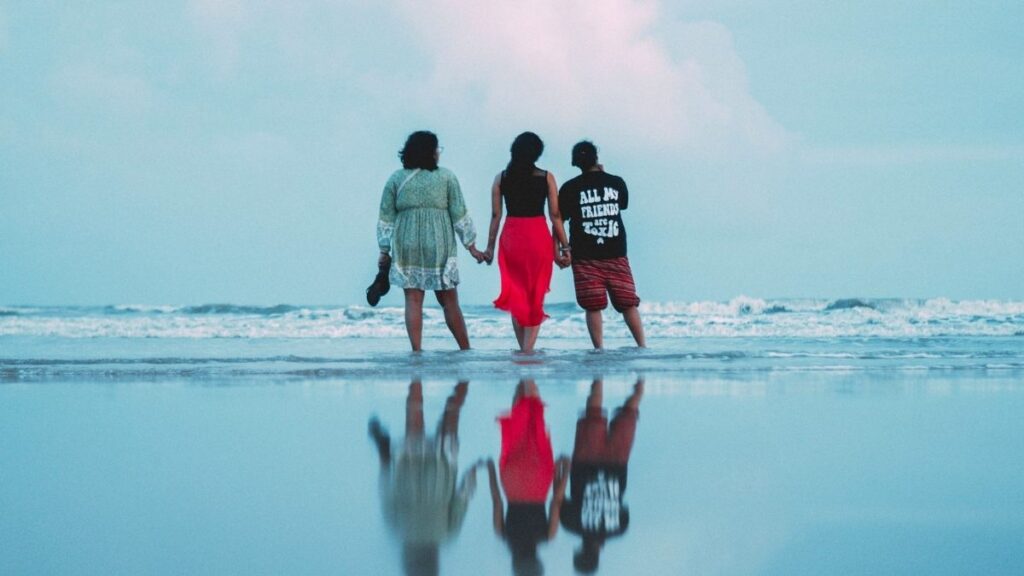 3 mensen op het strand die handen vasthouden